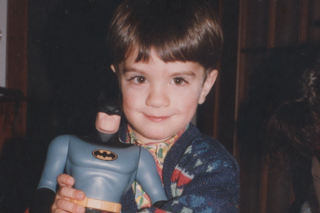 A very young Web Designer and Webflow developer holding on dearly to a big Batman figurine.